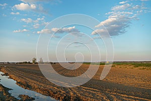 The background is a plowed field and beautiful clouds. Deep furrows in the ground after tractor work with a plow. Plowing the