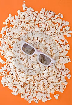 Background. Popcorn on a bright orange background. 3d glasses for watching a movie, top view