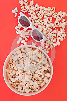 Background. Popcorn, cup and 3d glasses on a colored red background. Flat lay. Copyspace