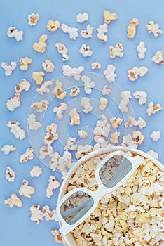 Background. Popcorn, cup and 3d glasses on a pastel blue background. Flat lay. Copyspace