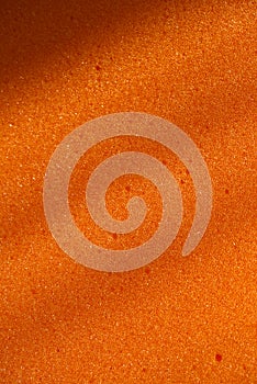 Background of porous foam rubber. Orange foam rubber. Packaging material