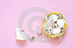 Background with quail eggs in the basket, rabbit and feathers.