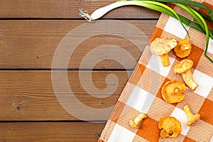 Background with raw golden chanterelle mushrooms. Seasonal mushrooms, harvest on a wooden table with a checkered napkin and green