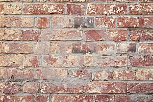 Background of red vintage brick wall, surface close-up. Colorful grunge texture of wall with peeling plaster, copy space