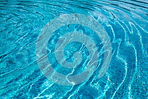 Background of rippled pattern of clean water in a blue swimming pool