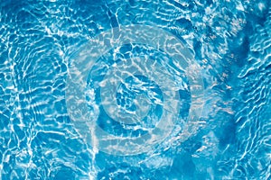 Background of rippled pattern of clean water in a blue swimming pool