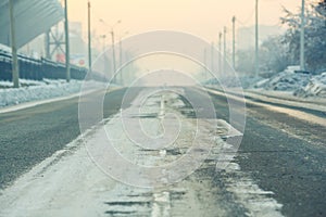 The background, road on an empty street in city, cold winter day with snow and reagents at dusk, aerial perspective