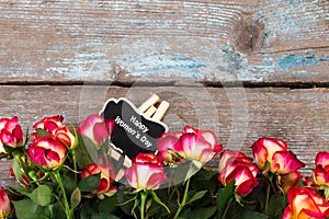 Background with roses and chalkboard on wooden table. Top view w