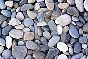 Background with round pebble stones. Stones beach smooth, flat lay texture in daylight. Top view. Summer day