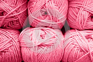 background of rows skeins of fluffy wool yarn for knitting soft red pink purple hue colors. toned in viva magenta