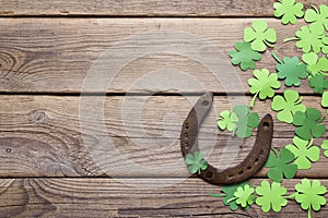 Background with rusty horseshoe and paper clover leaves on the o