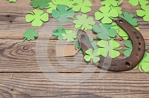 Background with rusty horseshoe and paper clover leaves on the o