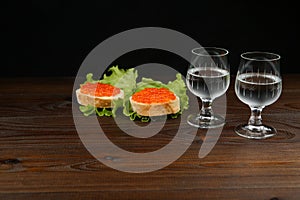 Background with sandwiches with red caviar. two glasses of cold vodka