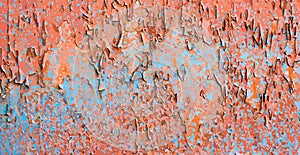 Background of shabby orange wall with blue spots. Bright texture of peeling paint on old worn wall.