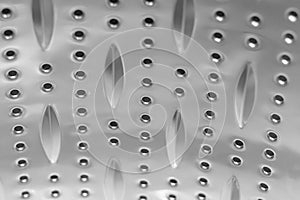 Background sheet of metal covered with lines of circular holes