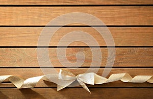 Background with shiny gold bow with ribbon on wooden table