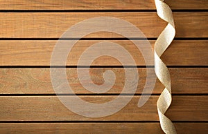 Background with shiny gold ribbon with ripples on wooden table