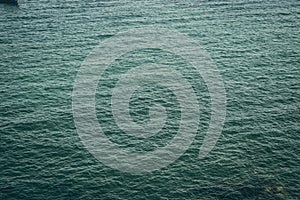 Background shot of aqua tropical sea blue water surface. Dark toned photo abstract sea ripples natural background. Ideal
