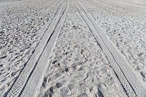 Background of soft beach sand with ATV tire tracks leading off into the distance, creative copy space for travel, leisure