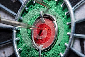 Background in soft focus with a darts board with a closeup of an arrow hitting the center