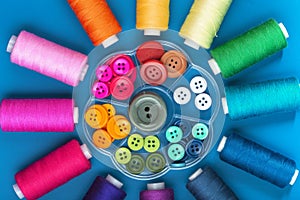 Background from spools of sewing threads and buttons of different colors, top view