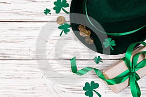 Background for St. Patrick's Day. Leprechaun hat, gold coins and clover shamrock on a white wooden background. Good
