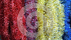 Background of striking palette of colorful shiny classic tinsel Garland. Red, yellow and blue color gradient. Winter accessories f