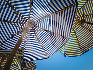 Background of striped colored beach umbrellas, view from the bottom, against the sky
