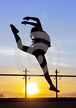 With the background of a sunset a dancer executes a jump photo