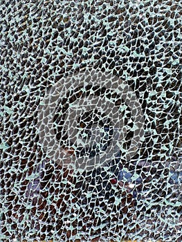 Background: surface of broken triplex glass shards on a black background, shattered transparent window pieces, cracks