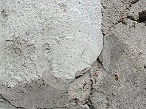 Background, surface texture. a layer of white peeling paint on rough gray concrete, cement, plastered wall.