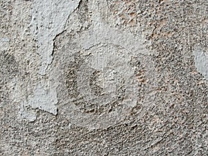 Background, surface texture. a layer of white peeling paint on rough gray concrete, cement, plastered wall.