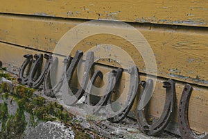 Background surface of very old and rusty horseshoes placed near the wall