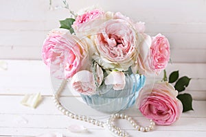 Background with sweet pink roses flowers in blue vase on white