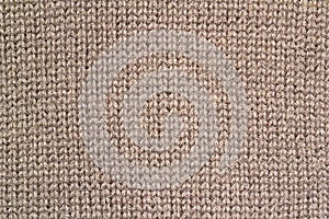 Background texture of beige pattern knitted fabric made of cotton or wool closeup