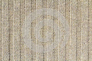 Background texture of beige pattern knitted fabric made of cotton or wool closeup