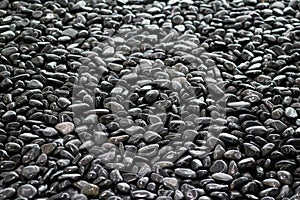 Background texture of big waterworn black pebbles or stones for use in decor and garden landscaping, close up view from above, sel