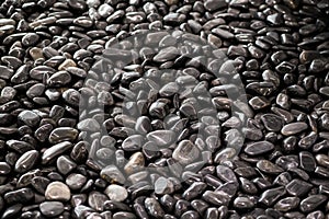 Background texture of big waterworn black pebbles or stones for use in decor and garden landscaping, close up view from above, sel