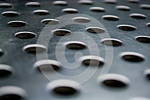 Background or texture from a gray and monophonic metal surface with symmetric and round openings.