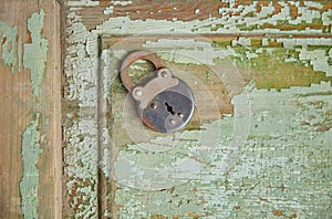 Background, texture. An old lock with a keyhole lies on an old wooden surface, the paint has peeled off.