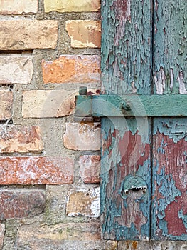 Background texture old wooden door with brown green broken paint and a yellow red brick wall