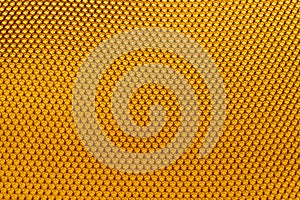 Background texture and pattern of a section of wax honeycomb from a bee hive filled without golden honey in a full frame view,
