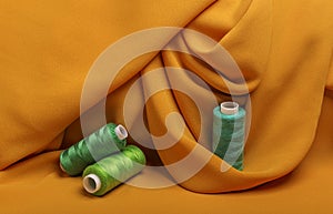 Background, texture, pattern wavy yellow silk fabric and sewing thread on spools