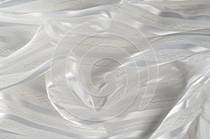 Background texture, pattern. White silk fabric, with a light strip. Closeup of rippled white silk fabric. Smooth elegant golden s