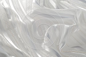 Background texture, pattern. White silk fabric, with a light strip. Closeup of rippled white silk fabric. Smooth elegant golden s