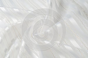 Background texture, pattern. White silk fabric, with a light strip. Closeup of rippled white silk fabric. Smooth elegant golden s