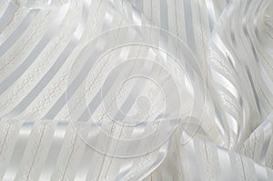 Background texture, pattern. White silk fabric, with a light strip. Closeup of rippled white silk fabric. Smooth elegant golden s