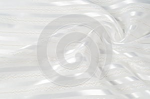 Background texture, pattern. White silk fabric, with a light strip. Closeup of rippled white silk fabric. Smooth elegant golden s