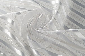 Background texture, pattern. White silk fabric, with a light strip. Closeup of rippled white silk fabric. Smooth elegant golden s