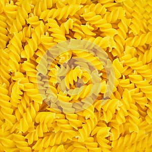 Background the texture of raw pasta closeup. Italian Fusilli or Rotini helix shaped Macaroni Pasta raw food close up